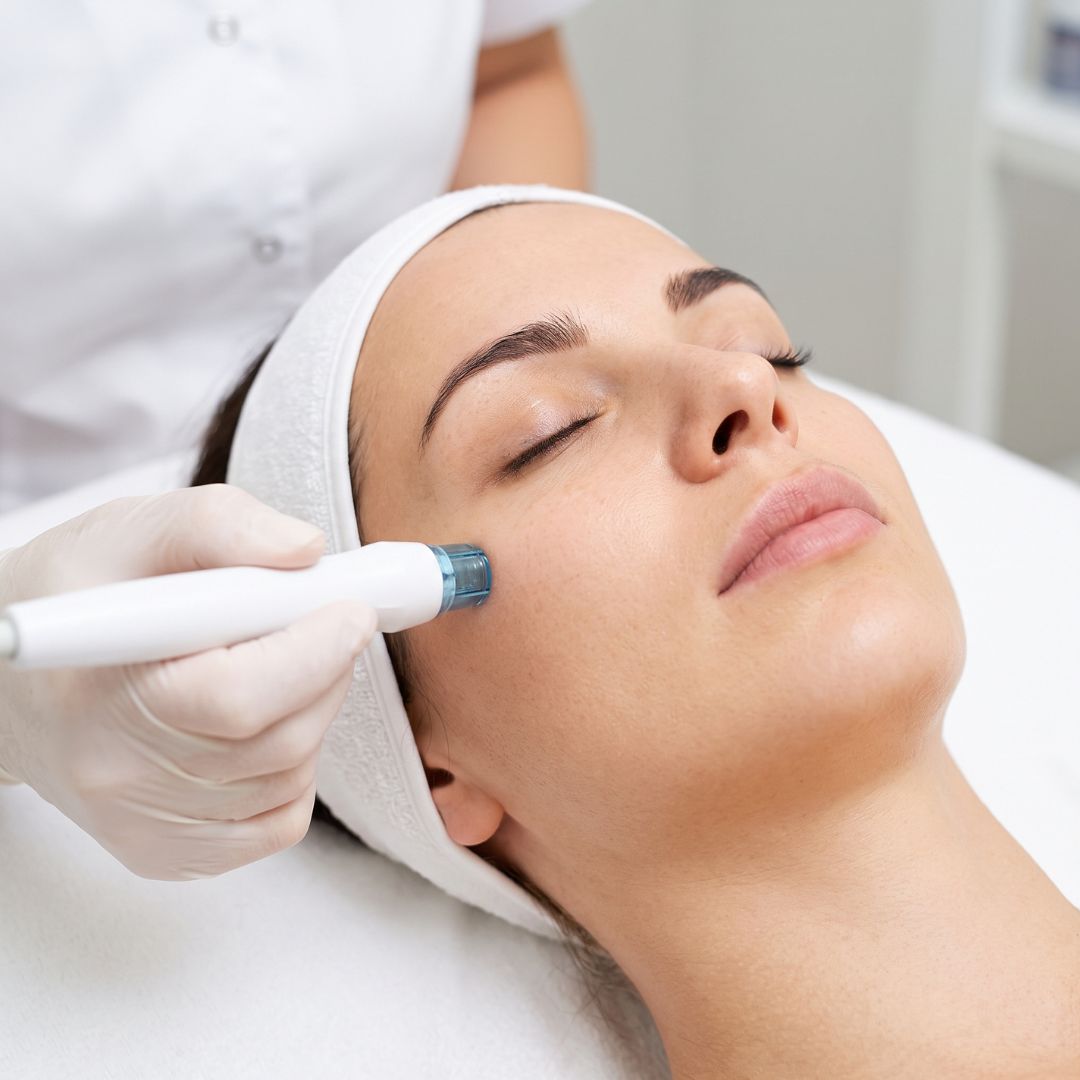 Close-up of a professional skincare specialist applying a clinical treatment to a client's face with a specialized tool.